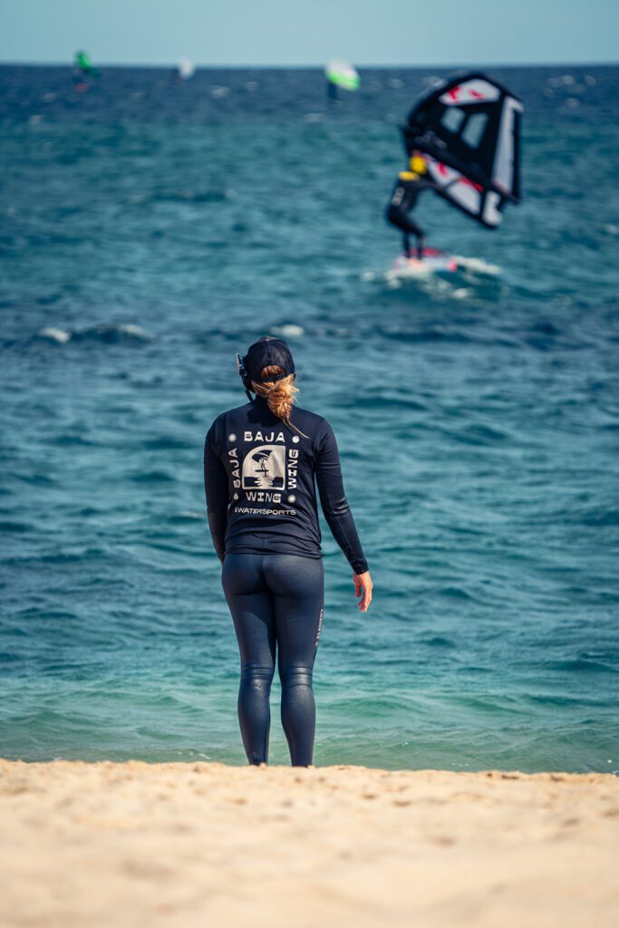 Instructor watching wing foiling student from the beach