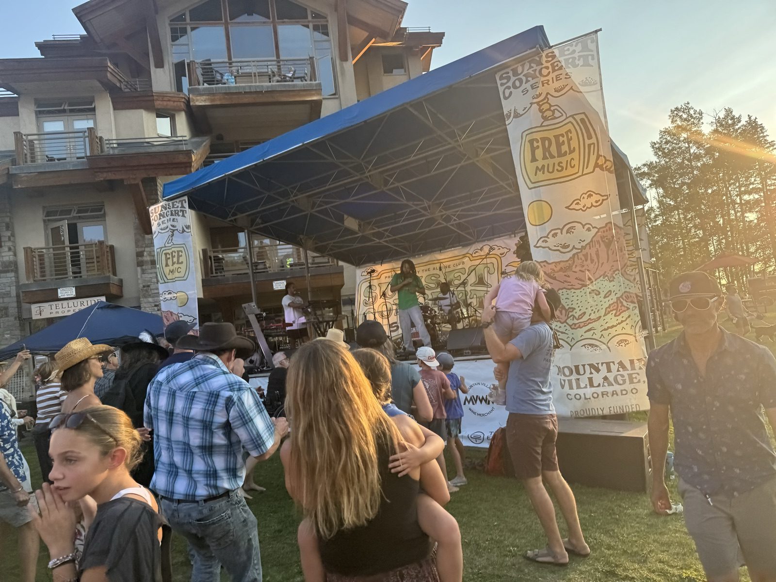 Crowd dancing at the free Sunset Concert Series stage in Mountain Village at golden hour