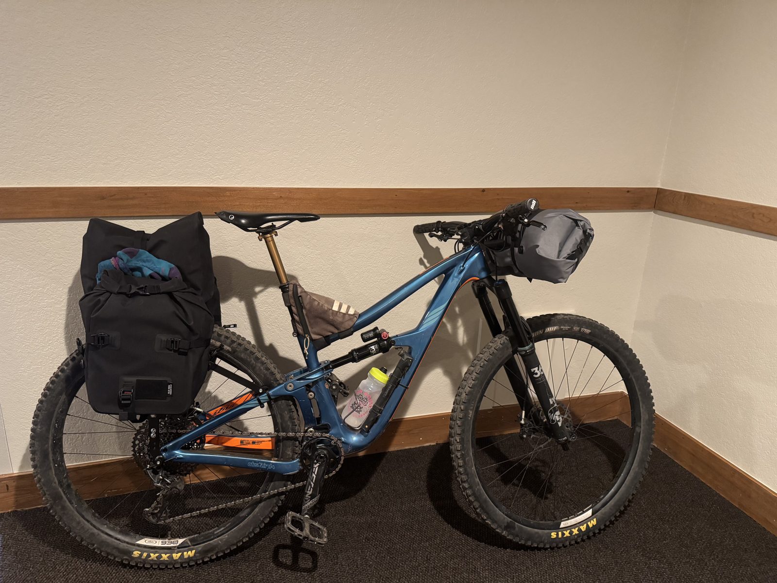 Loaded Ibis Ripmo mountain bike with rear rack and panniers in a living room the night before a bikepacking trip