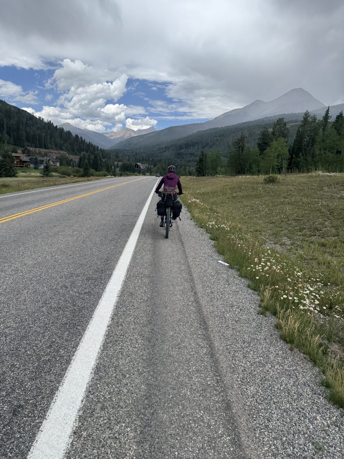 Cyclist with loaded panniers riding the paved highway shoulder with mountain views near Durango